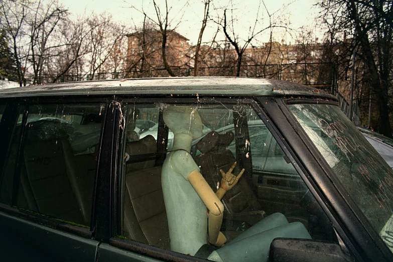 an old car with two mannequins and a window rain curtain