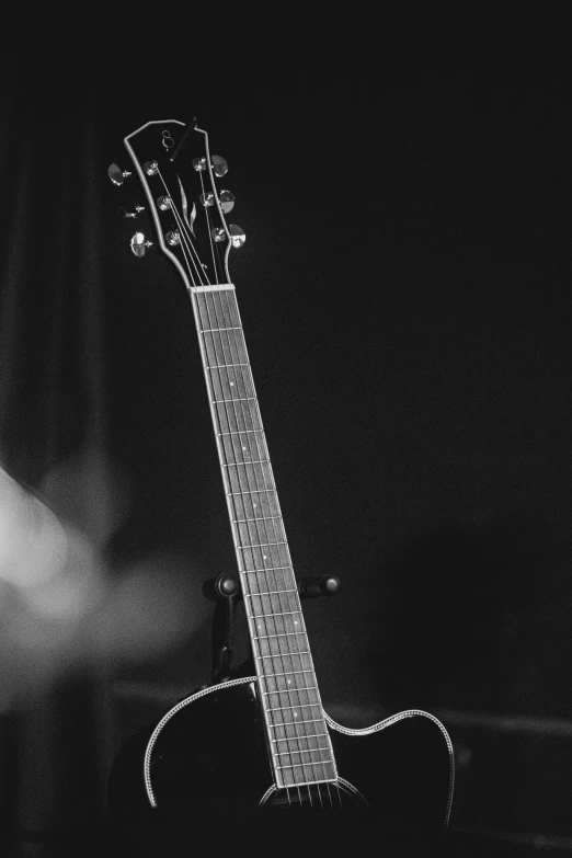 black and white po of acoustic guitar on stage