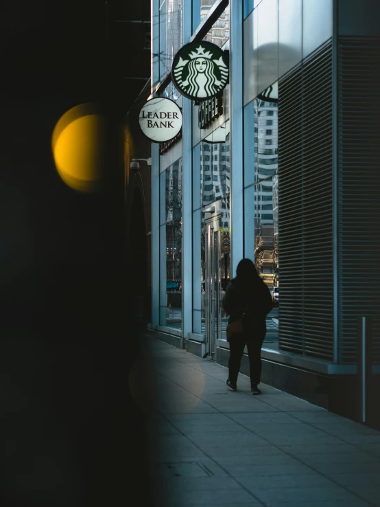 a person walking by a starbucks shop at night