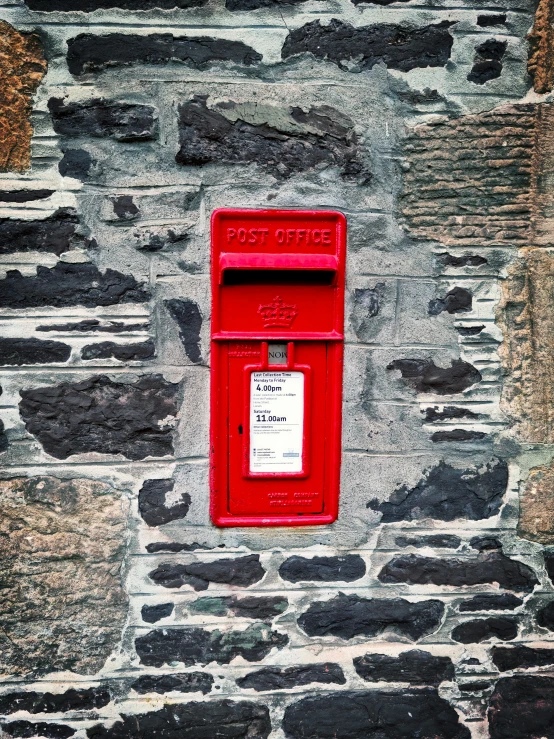 a red mailbox mounted to the side of a brick wall