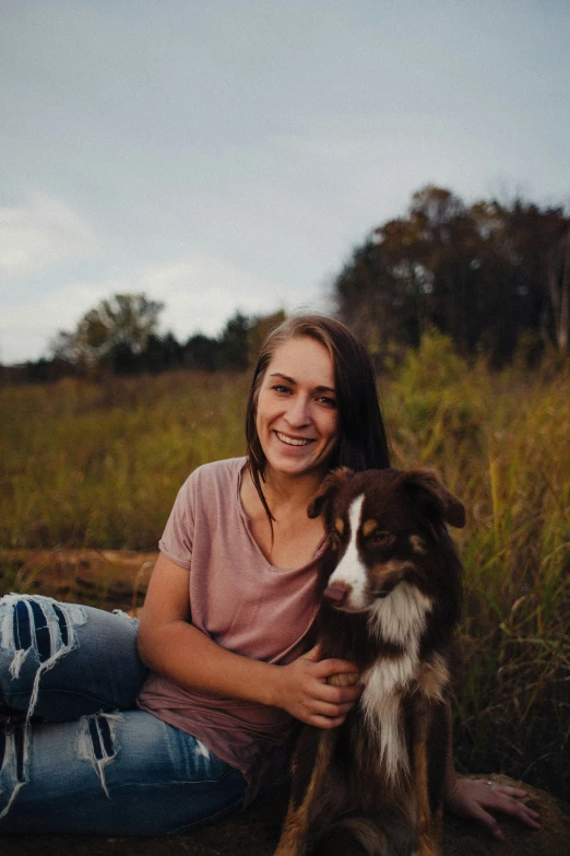 a woman and a dog on the ground in a field