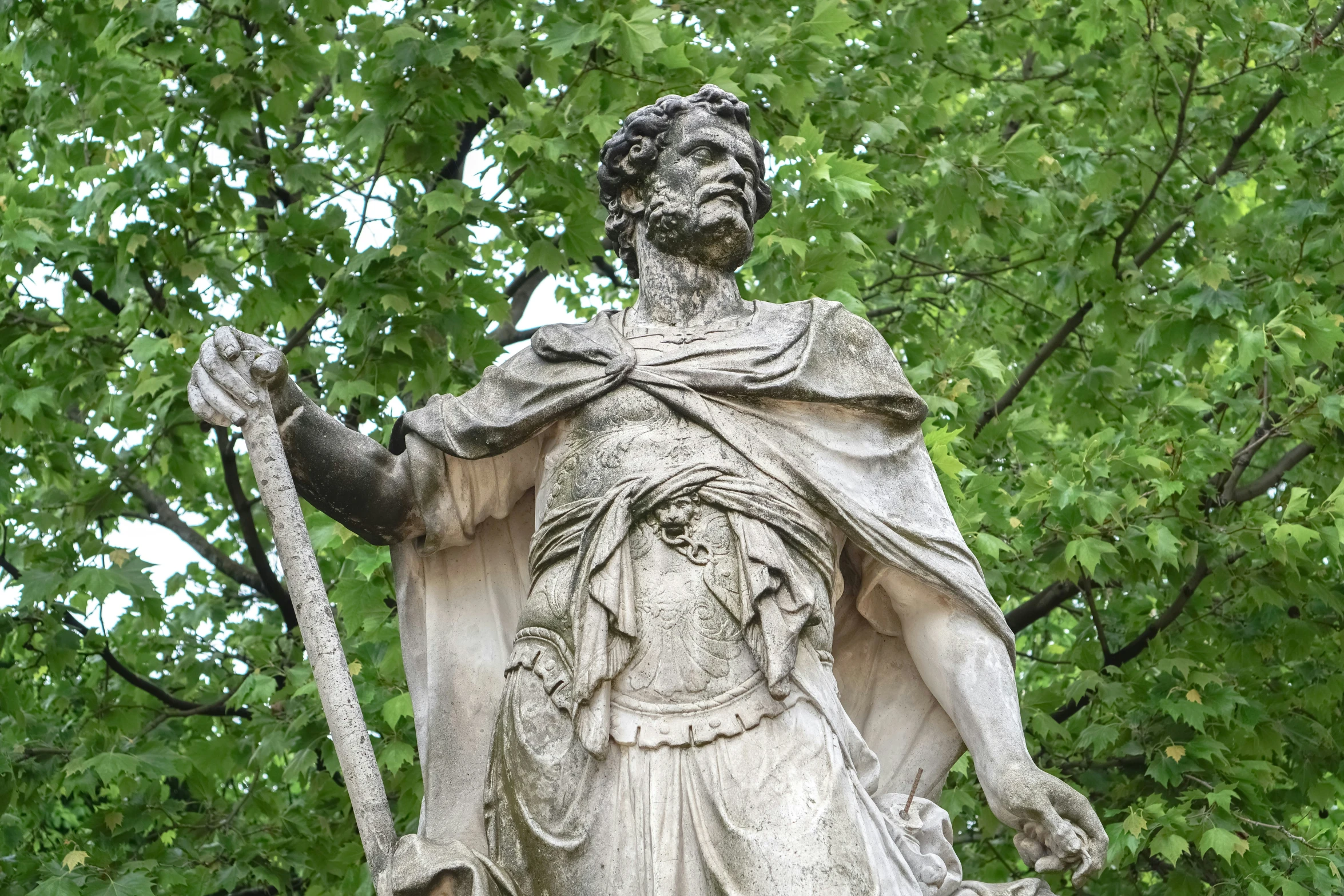 a statue sitting next to a tree filled forest