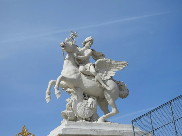 a large statue on a building that has a blue sky in the background