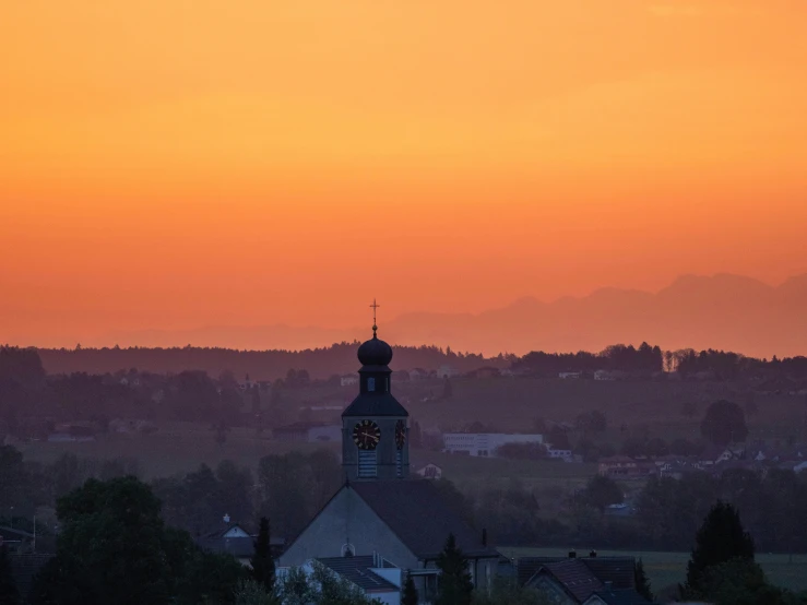 a clock tower at sunset next to an urban area