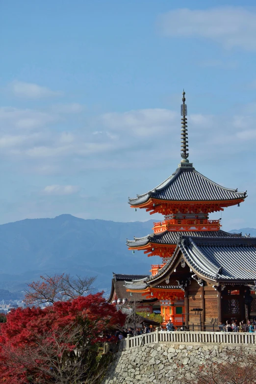 a tall pagoda stands near trees with red flowers