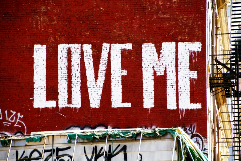 graffiti that reads love me on a red brick wall