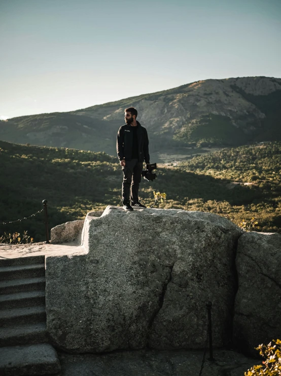 a skateboarder standing on top of a large rock