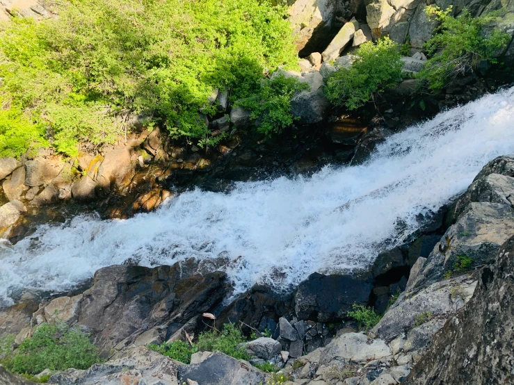 a person sitting on the rocks next to a waterfall