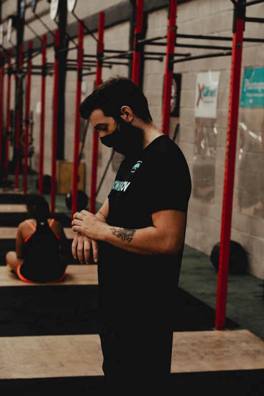 man wearing black standing in the middle of a crossfit area