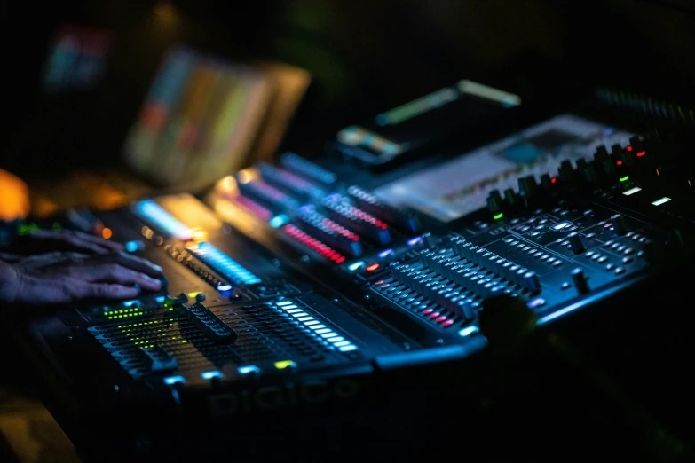 a mixing console sits illuminated by the glow of a bright colored light