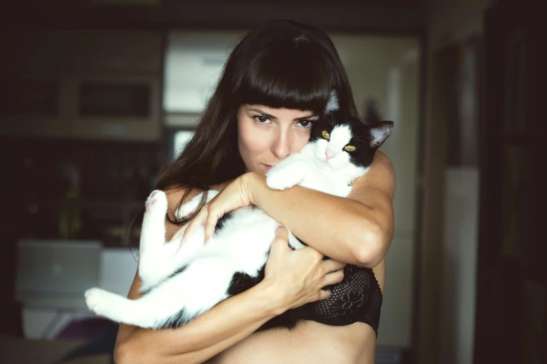 a lady wearing a bikini holds a cat in her arms