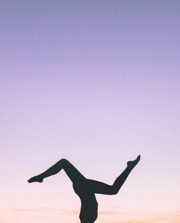 the silhouette of a woman wearing an open leg silhouetted against the sunset