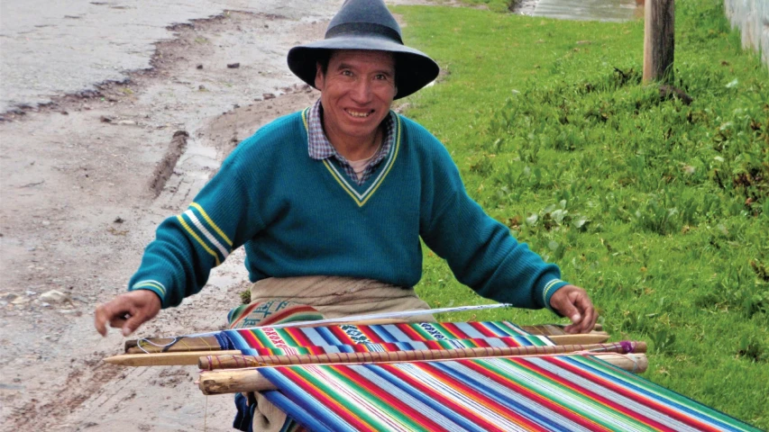 a woman smiles while hing a small cart carrying a woven blanket