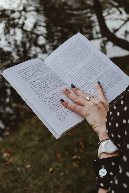 a woman's hand holding a book open