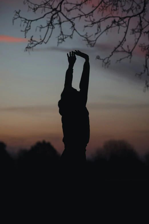the silhouette of a person reaching up for a frisbee