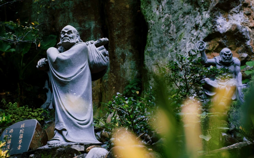 there is a statue of jesus next to some rocks and plants