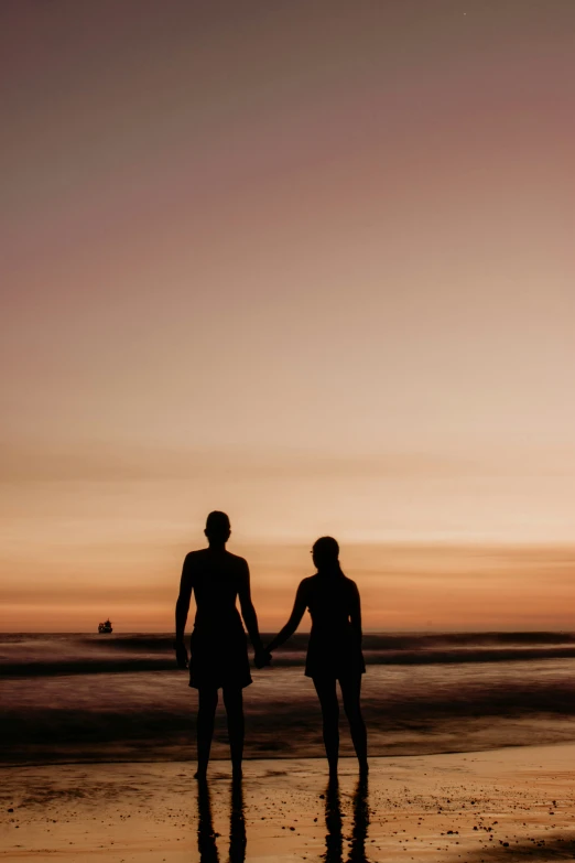 a couple on the beach holding hands and facing each other