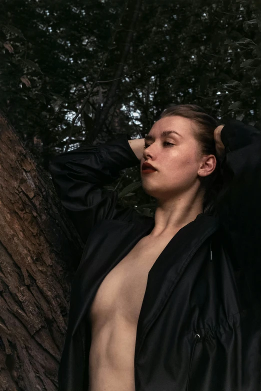 a  woman poses against a large tree