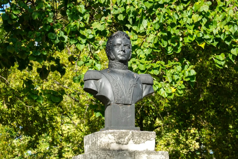 a statue in front of green trees and leaves