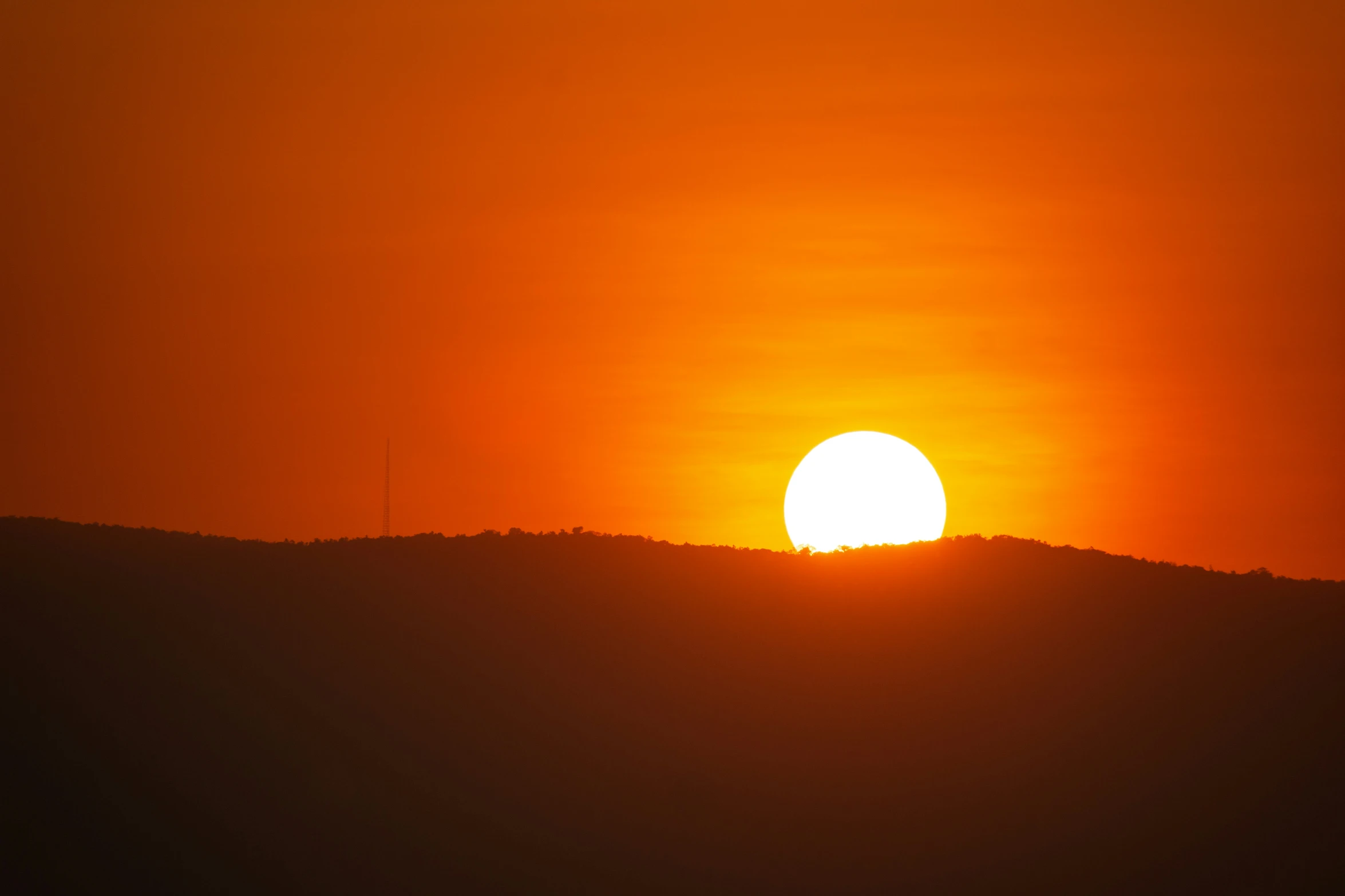 the sun is setting behind a hill