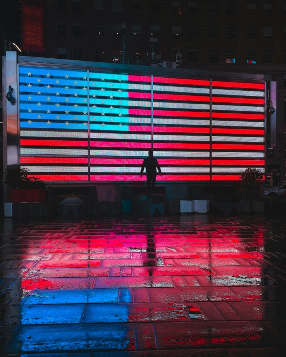 a building lit with lights and reflecting in the wet pavement