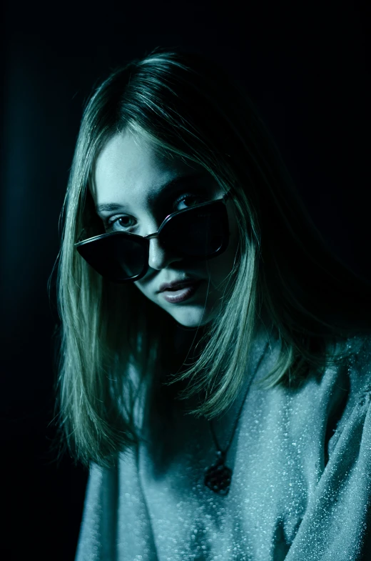 a woman with sunglasses is standing in the dark