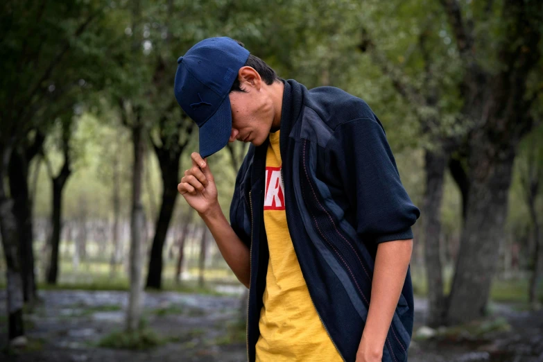 a boy in the woods talking on a cell phone