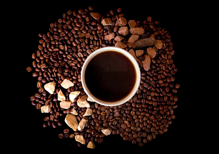 a cup of coffee sits on some coffee beans