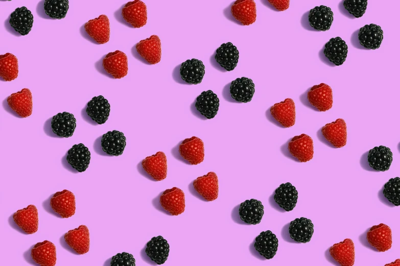 raspberries and blackberries on a pink surface
