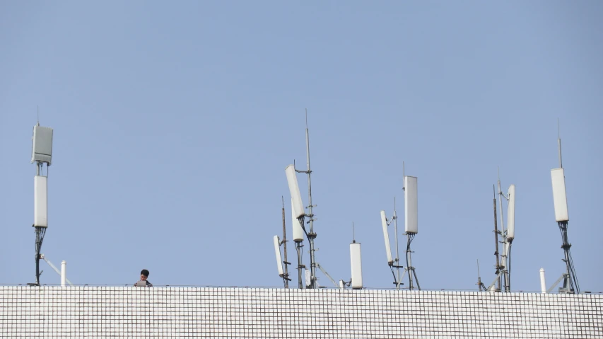 a person standing on a ledge in front of multiple cell towers