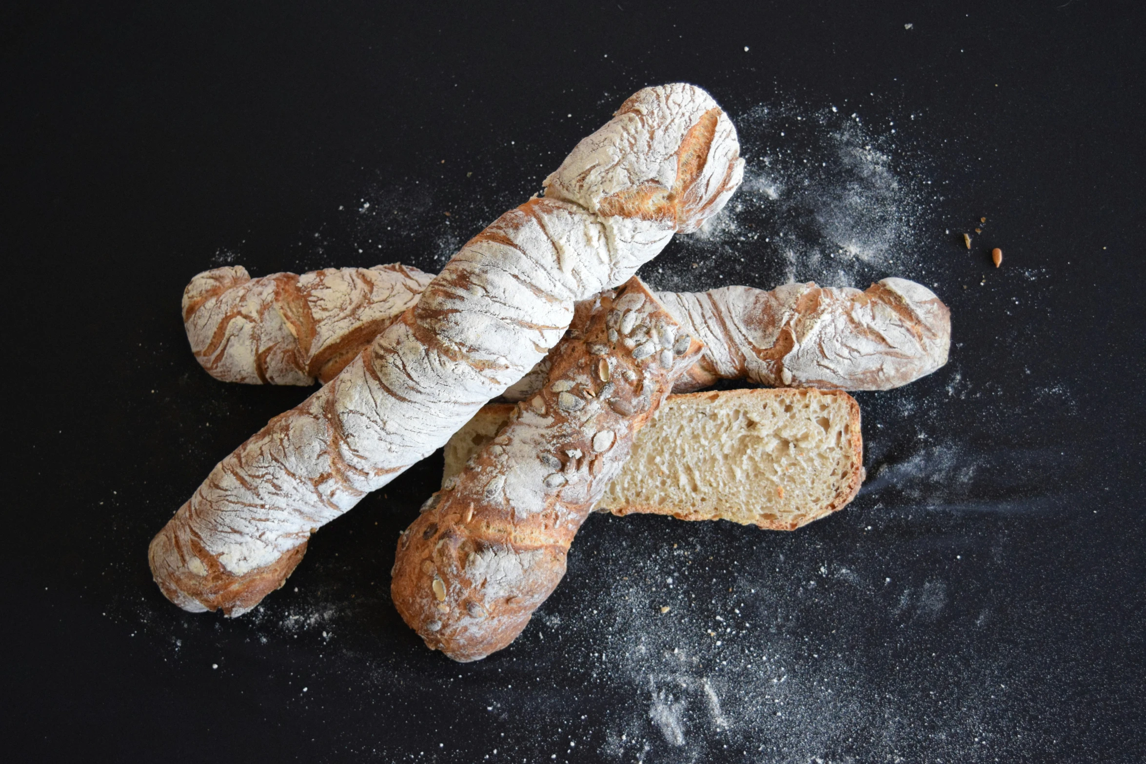 bread sticks and some dough on a black surface