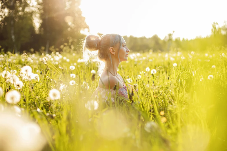 a girl in a field surrounded by dandelions