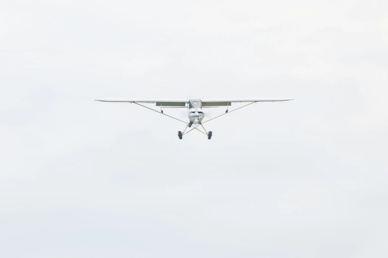 a small airplane flying through the sky with two men standing on it