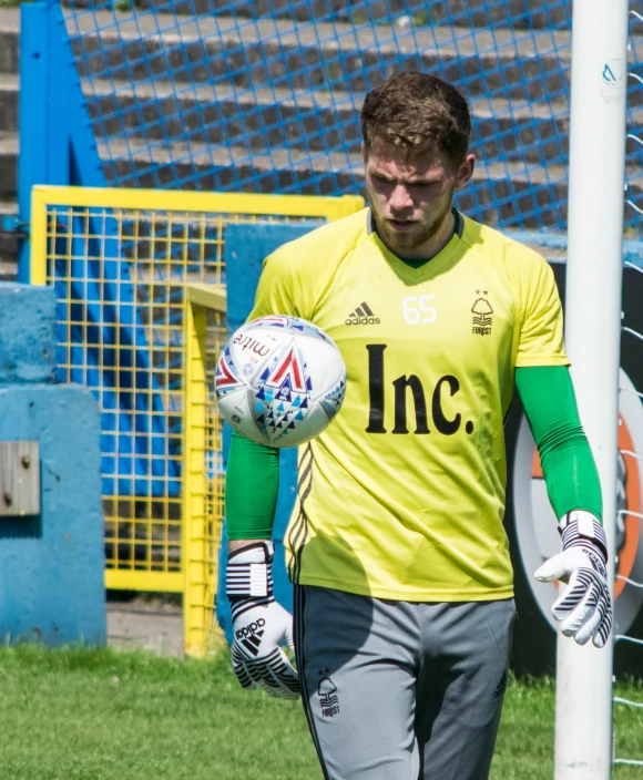 a man in yellow holds a ball at the field