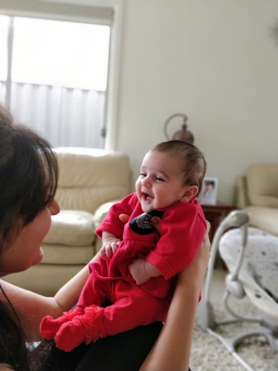 a woman holding a baby while holding a cell phone in her hand