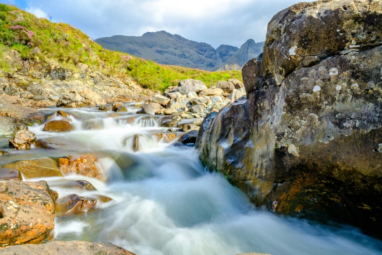 rocks surrounding a river running between mountains