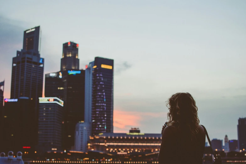 a young person with long hair standing in front of a city skyline