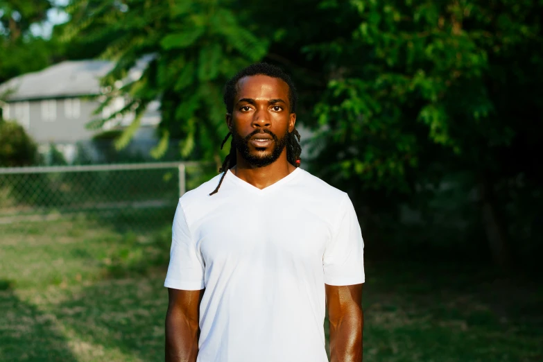 a young man is standing in a field near trees