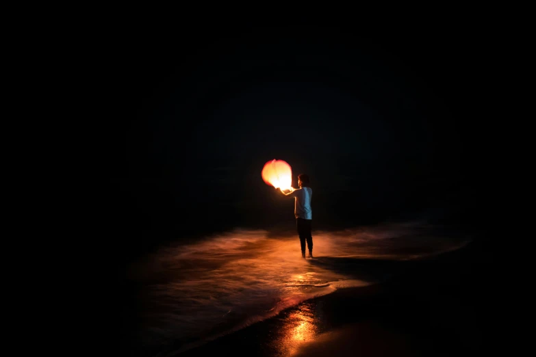 a person standing on the sand holding a light