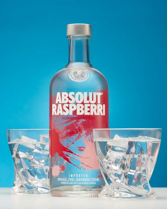 a bottle of absolut raspberry vodka next to some glasses