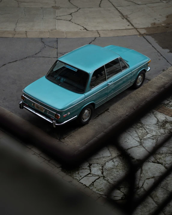 an overhead s of a blue car sitting on the pavement