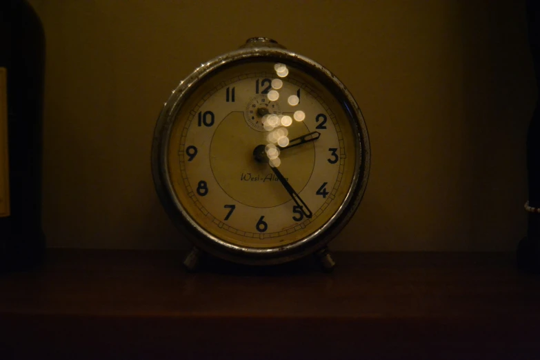 an alarm clock with lights next to bottles