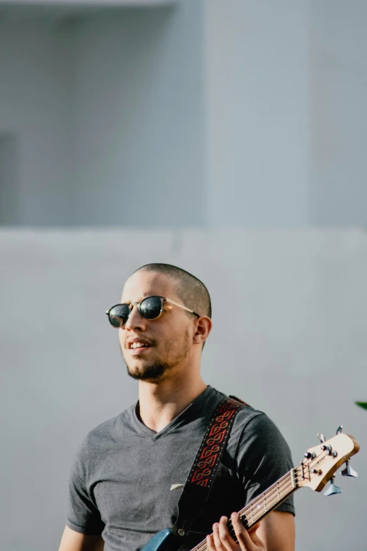 man with sun glasses playing bass guitar outside