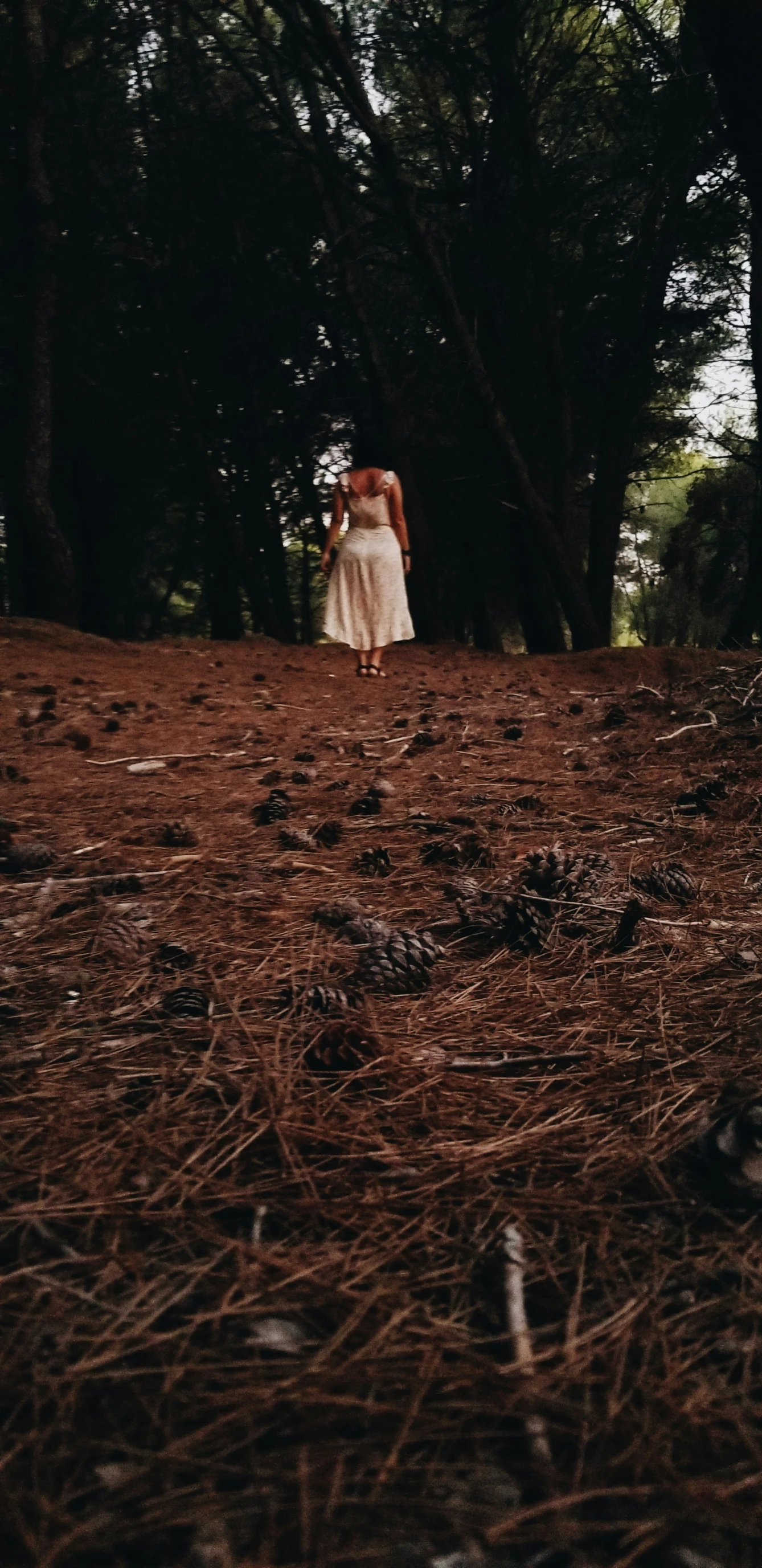 a woman in a white dress is walking down the dirt