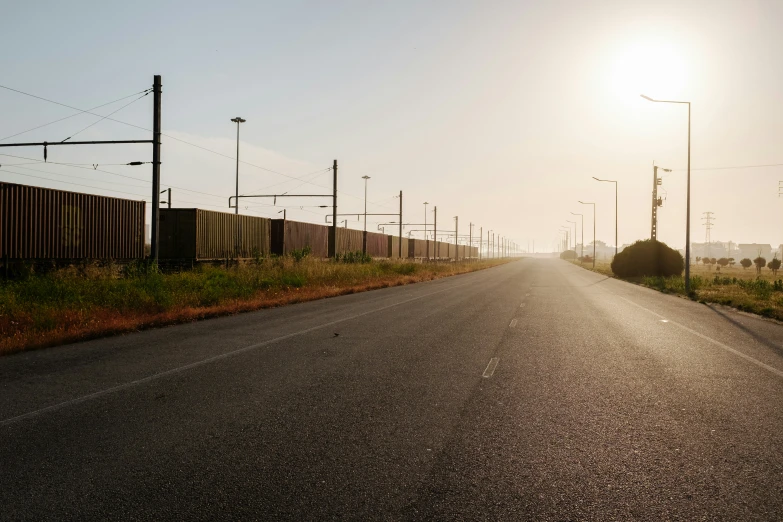 a rural road with a rusted fence and grass on both sides