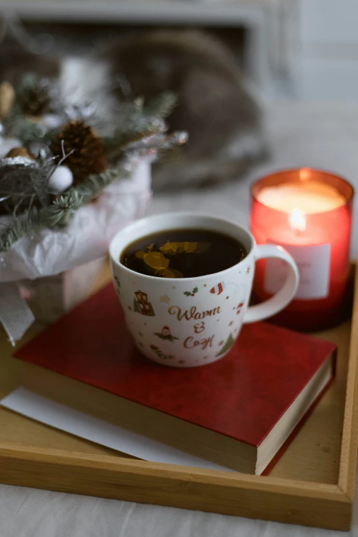 a coffee cup sits in front of a lit candle on a tray