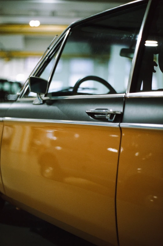 there is a small old yellow car in the parking garage