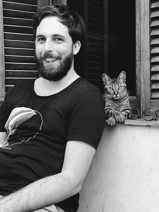 a man and his cat sitting outside of a window