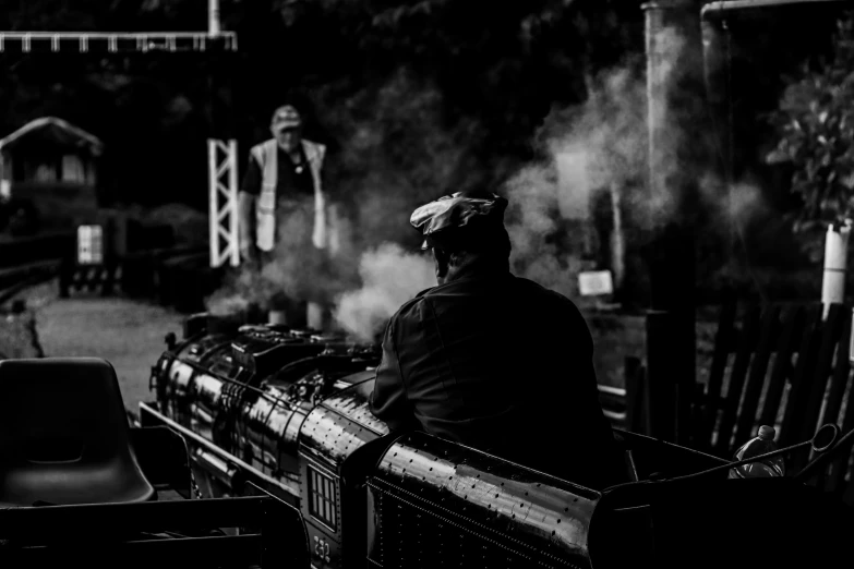 a man riding on the back of a train with smoke coming out of it