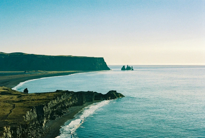 an ocean shoreline with some very cliffs in the background